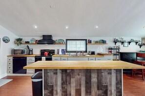 Una cucina moderna con isola in legno, mobili bianchi e cappa aspirante nera.