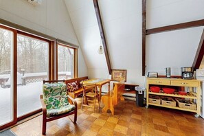 Ein gemütliches Zimmer mit Holzboden, einem Esstisch, einer Bank, einem Stuhl und einer Küchenzeile mit einem Wagen.