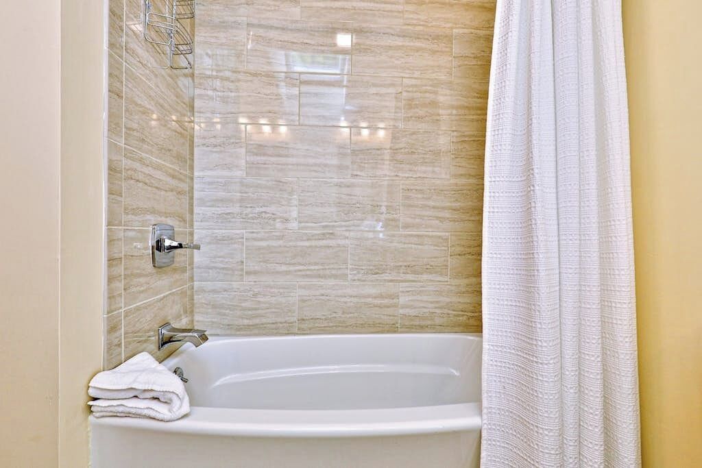 Une salle de bain avec une baignoire, une douche et un mur carrelé.