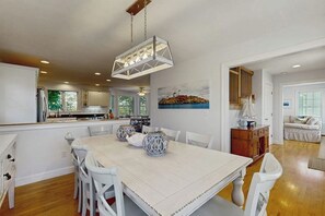 A spacious dining area with a large table, white chairs, and decorative vases. - Bright dog friendly coastal home close to beaches (York)