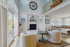 A spacious living room with a fireplace, a round table, and two ottomans. - Bright dog friendly coastal home close to beaches (York)