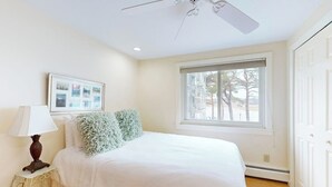 A bedroom with a bed, a ceiling fan, a window, a nightstand, and a lamp. - Ocean View, Riverfront Home w/ Marsh Views, 2 Decks, Kayaks - Walk to Beach (Wells)