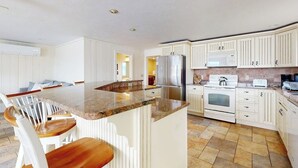 A kitchen with white cabinets, a granite countertop, a stainless steel refrigerator, and a microwave. - Ocean View, Riverfront Home w/ Marsh Views, 2 Decks, Kayaks - Walk to Beach (Wells)