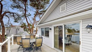 A covered patio with a table and chairs, a sliding glass door, and a view of a body of water. - Ocean View, Riverfront Home w/ Marsh Views, 2 Decks, Kayaks - Walk to Beach (Wells)