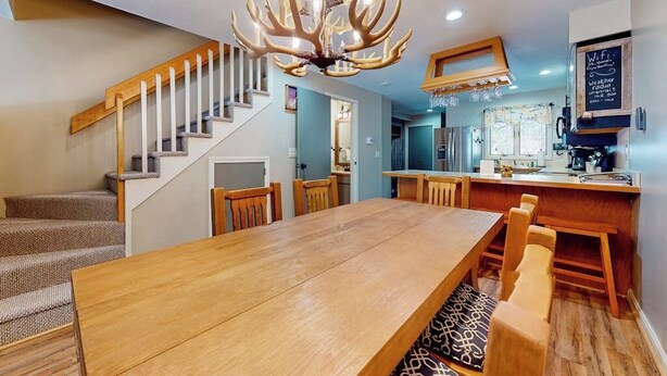 Eine moderne Küche mit einem Holzesstisch, einer Treppe und einem auffälligen Chandelier aus Geweihen.