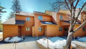 Ein zweistöckiges Holzhaus mit einer Veranda und einem Baum davor, bedeckt mit Schnee.