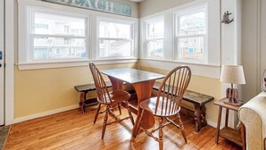 Una habitación con una mesa y sillas de madera, un banco, una lámpara y un letrero que dice 'BEACH'.
