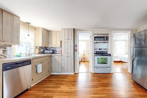 A modern kitchen with wooden cabinets, stainless steel appliances, and a dishwasher. - Comfortable home steps from beach with deck, grill, & washer/dryer (Hampton)