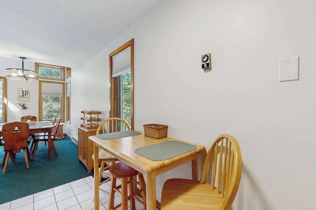Un coin repas avec une table en bois, des chaises et une vue par la fenêtre.