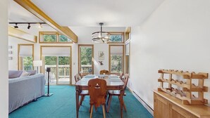 Ein Essbereich mit Holztisch und Stühlen, einem Deckenventilator und großen Fenstern.