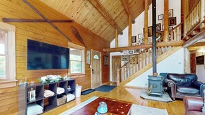 Un intérieur en bois avec une cheminée, un escalier et un espace de vie comprenant un canapé et une table basse.