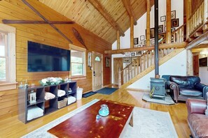 Ein Holzinnenraum mit Kamin, Treppe und Wohnbereich mit Sofa und Couchtisch.