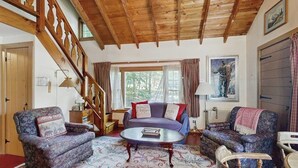 Una sala de estar acogedora con una escalera de madera, un conjunto de sofás y una mesa de centro.