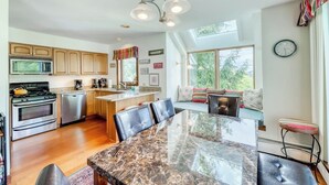 A modern kitchen with a large island, stainless steel appliances, and a dining area with a glass table.