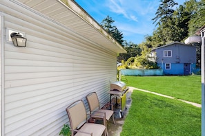 A residential property with a patio area featuring a grill, chairs, and a table.