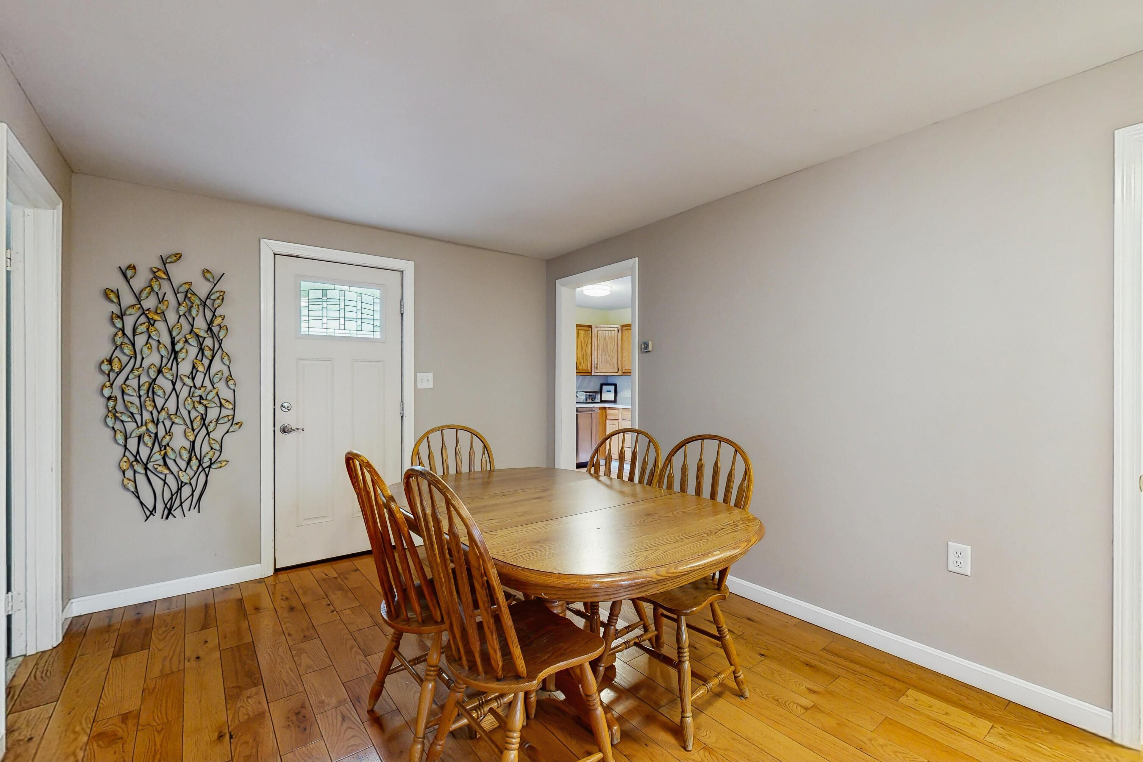 A dining room with a wooden table and chairs, a decorative wall piece, and a door with a window.