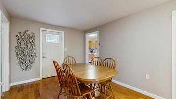 A dining room with a wooden table and chairs, a decorative wall piece, and a door with a window.