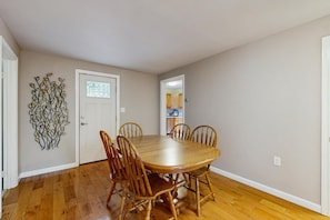 A dining room with a wooden table and chairs, a decorative wall piece, and a door with a window.