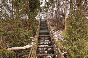 A wooden staircase leading into a forested area with snow on the ground.