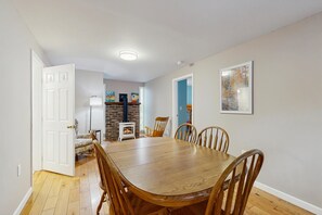 A dining area with a wooden table and chairs, a fireplace, and a door leading to another room.