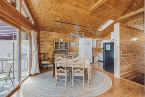A wooden interior with a dining table, chairs, a chandelier, and a kitchen area. - Summer Fun, Lake View, Firepit, Outdoor grilling, walk to the lake (Naples)