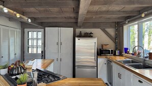 A kitchen with a wooden countertop, stainless steel appliances, and a window with a view of trees.