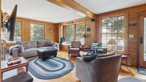 Ein großzügiges Wohnzimmer mit einer großen Couch, Sesseln, einem Couchtisch und einem Fernseher.