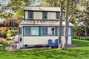 A two-story house with a front porch, a tree, and a lawn. - Charming oceanfront house with incredible beach views, BBQ area & firepit (York)