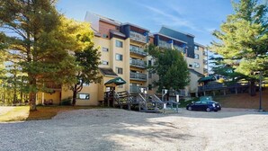 Een meerlaags hotel met een parkeerplaats, terras en een overdekte doorgang.