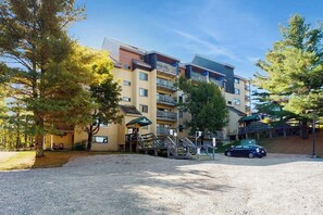 Ein mehrstöckiges Hotel mit Parkplatz, Außenbereich und überdachtem Gang.