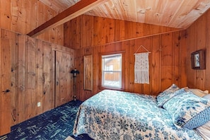 Une pièce en bois avec un lit, une fenêtre et une porte.