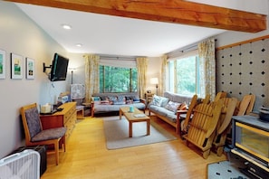 Ein gemütliches Wohnzimmer mit einer Sofagarnitur, Holzstühlen, einem Fernseher und einem Kamin.