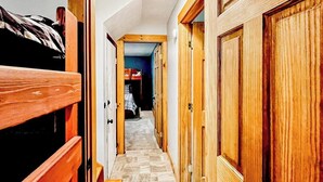 A narrow hallway with wooden doors and a bunk bed on the left. - Immaculate All-Season Retreat with Must-See Game Room! (Bethel)