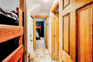 A narrow hallway with wooden doors and a bunk bed on the left. - Immaculate All-Season Retreat with Must-See Game Room! (Bethel)