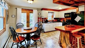 A kitchen with a wooden island, white cabinets, and a dining area with a round table and chairs. - Immaculate All-Season Retreat with Must-See Game Room! (Bethel)