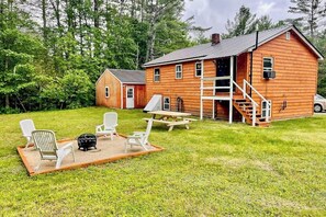 A wooden cabin with a porch, outdoor seating, and a fire pit. - Immaculate All-Season Retreat with Must-See Game Room! (Bethel)