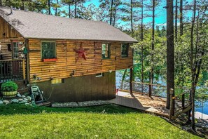 Eine Blockhütte mit Sternenverzierung, einer Terrasse und Blick auf den See.