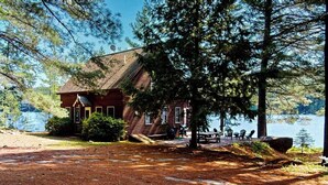 A lodge with a wooden exterior, a dock, and a view of a lake. - Tranquil Lakefront Retreat with large outdoor patio, beach and Stunning Views (Denmark)