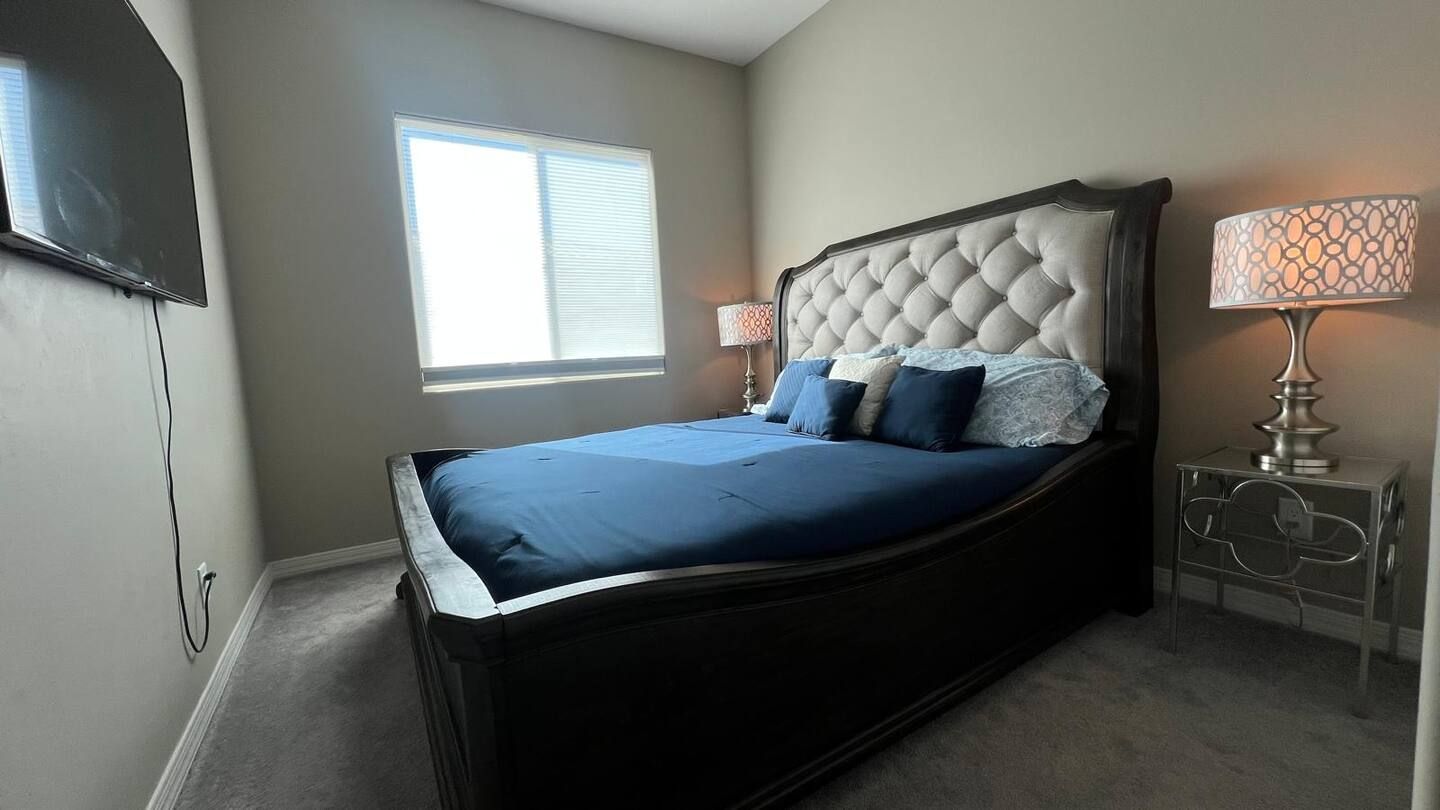 A bedroom with a large bed, a bedside table, a lamp, and a window.