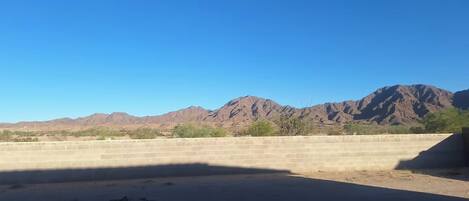 A desert landscape with mountains in the background and a concrete wall in the foreground.
