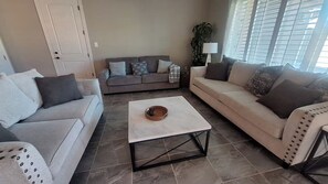 Ein Wohnzimmer mit zwei Sofas, einem Couchtisch und einer Tür.