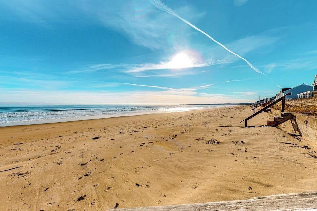 Une plage avec une promenade en bois menant à un bâtiment doté d’un balcon.