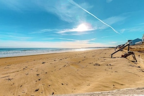 A beach with a wooden walkway leading to a building with a balcony. - Lovely oceanfront home with balcony, central AC, & washer/dryer (Wells)