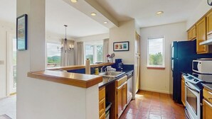 A modern kitchen with a central island, built-in appliances, and large windows.