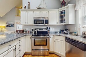 A kitchen with white cabinets, a stainless steel stove, a microwave, and a dishwasher.