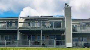 A multi-story building with balconies, a central chimney, and a flat roof.