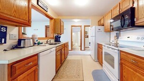 A kitchen with wooden cabinets, a microwave, a stove, and a refrigerator.