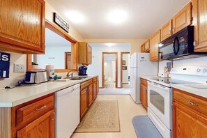 Une cuisine avec des meubles de rangement en bois, un four à micro-ondes, une cuisinière et un réfrigérateur.