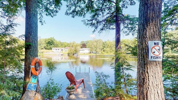A lakeside dock with a chair, a no-fishing sign, and a life preserver attached to a tree. - Entire lakefront home on Togus Pond with decks, canoe, firepit & great view (Augusta)