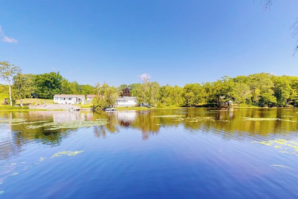 A serene lakeside view with a house and lush greenery.